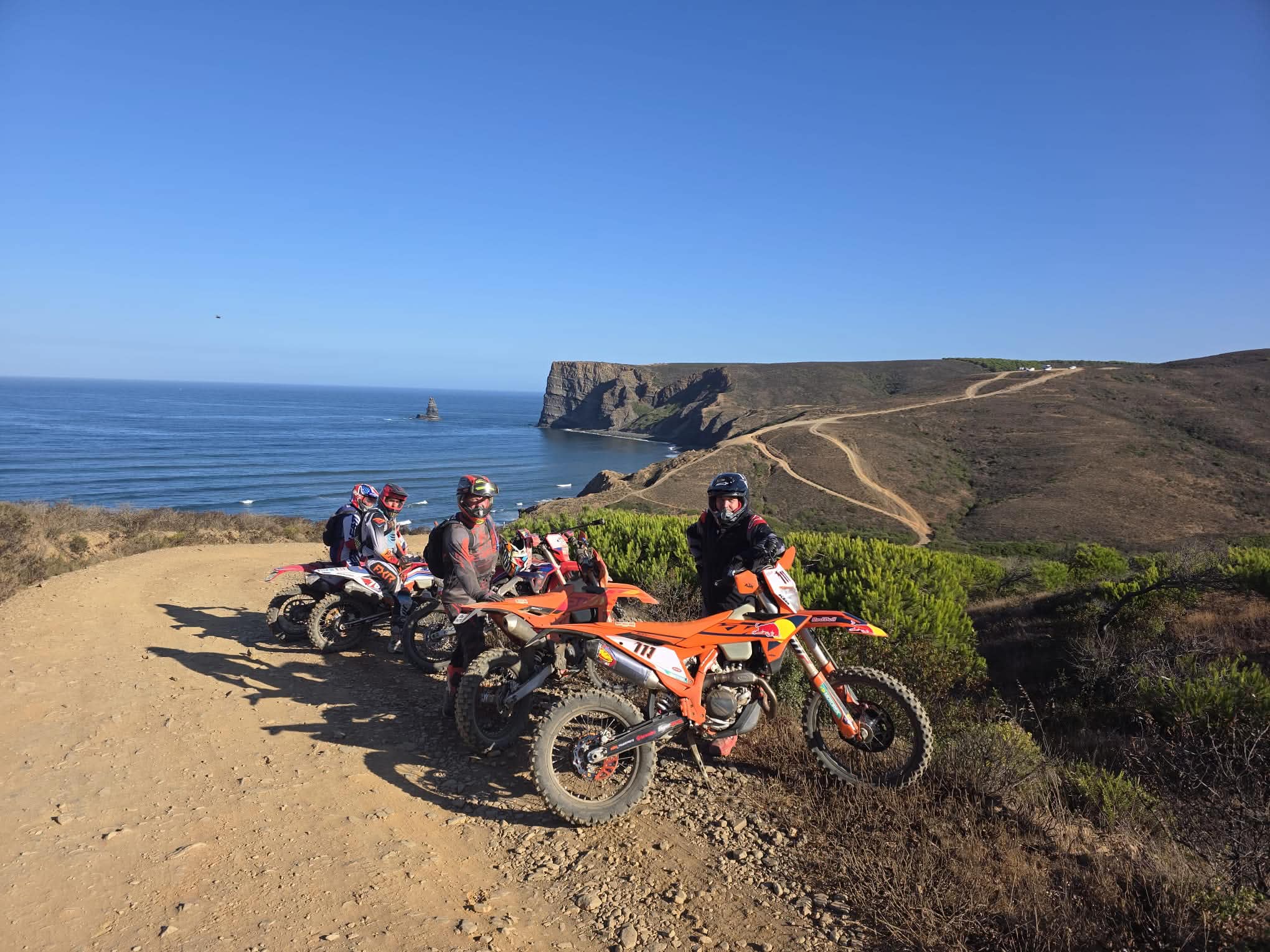 Enduro riders on a coastal cliff trail overlooking the Algarve ocean