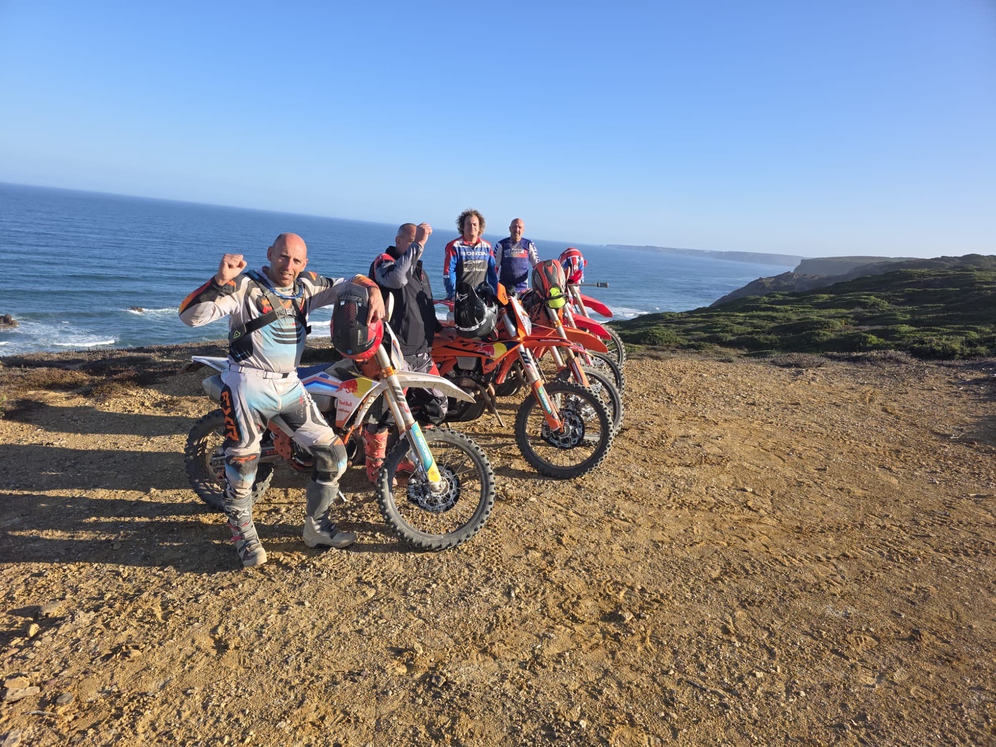 Tour group celebrating on a coastal cliff during the Full Day Enduro Tour.