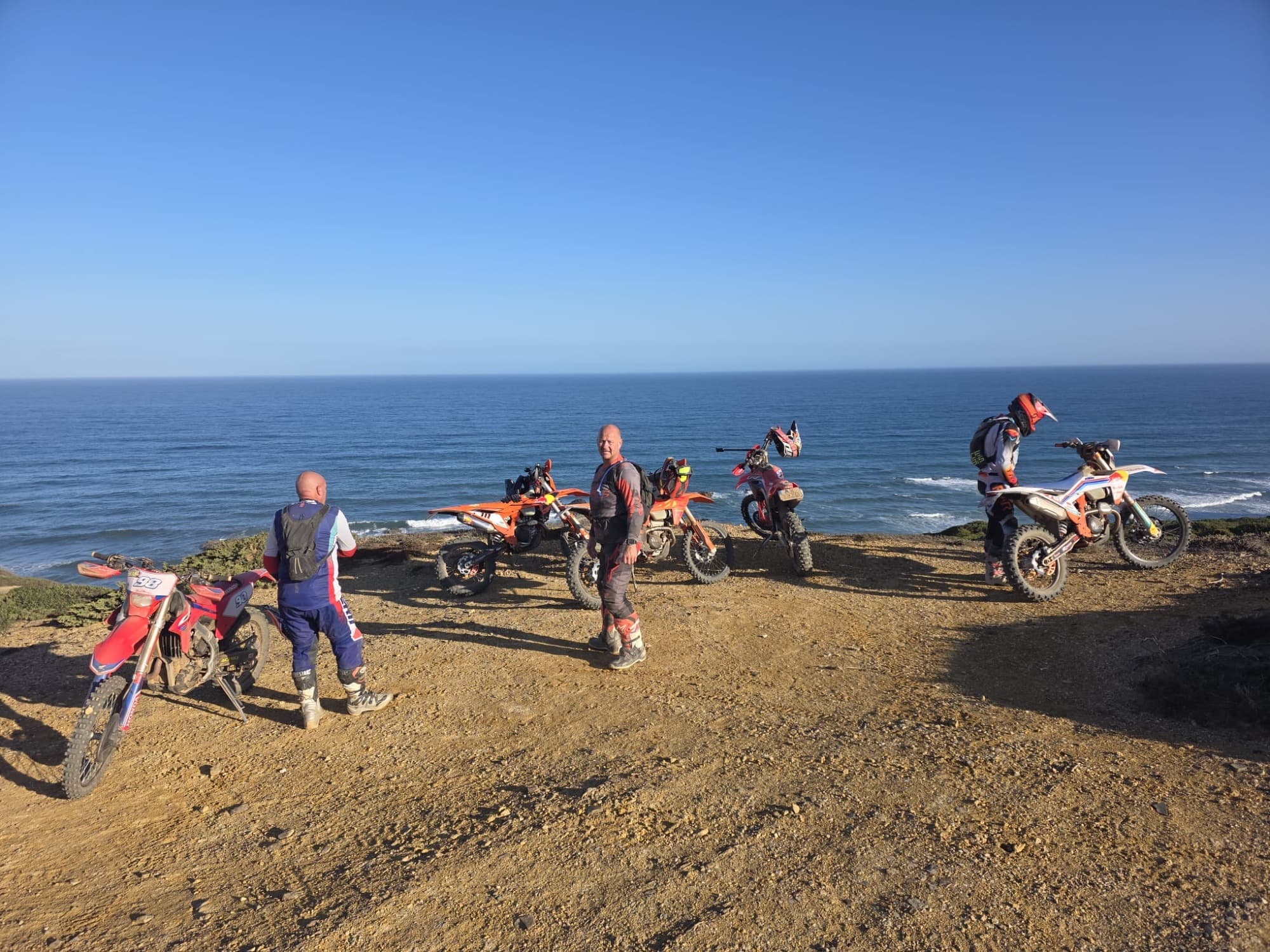 Riders with their bikes on a clifftop trail during the Full Day Enduro Tour.