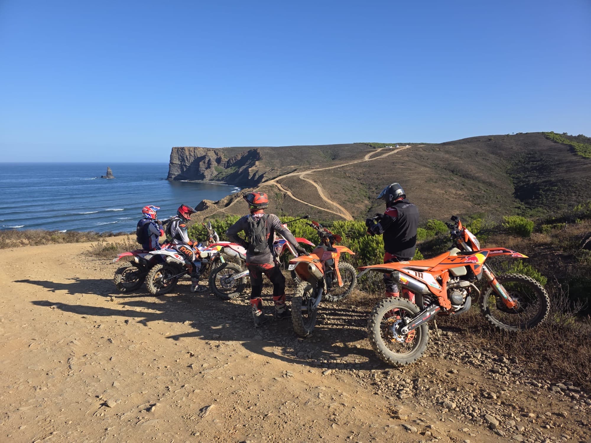 Riders paused on an Algarve trail with the coast behind them