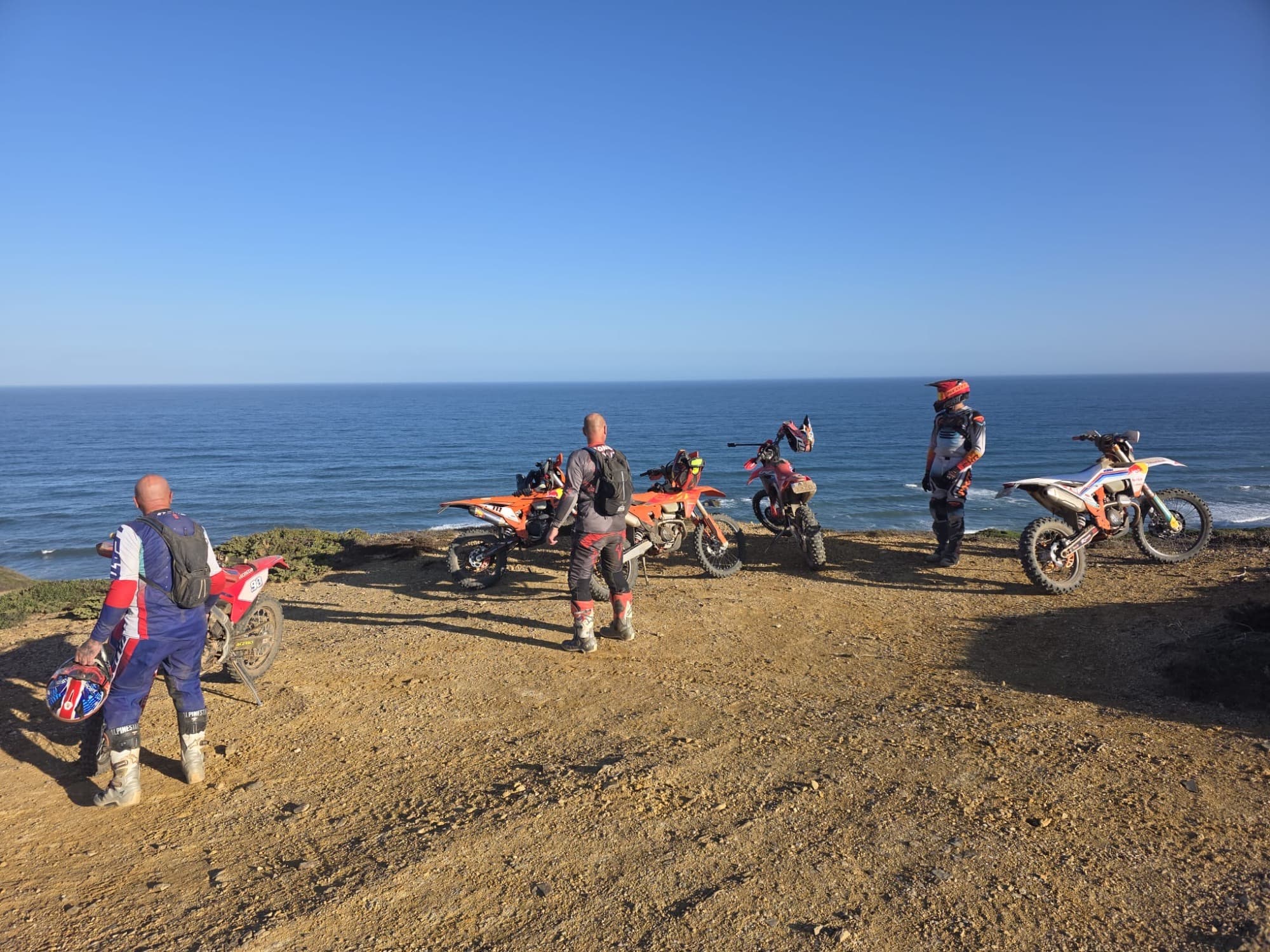 Enduro riders taking in the ocean view from a coastal cliff trail in the Algarve