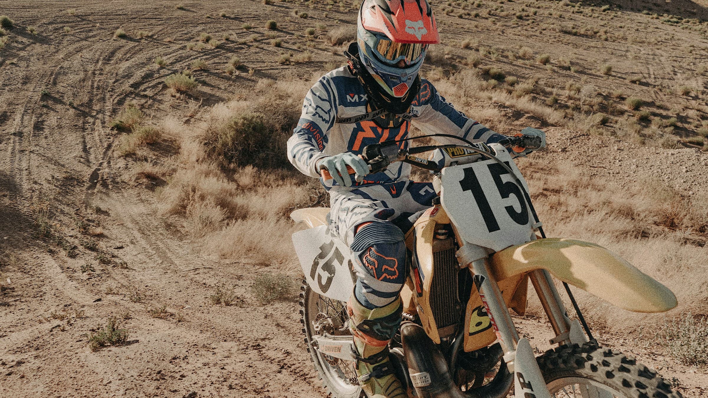 Dirt bike rider in Fox gear paused on a dry scrubland trail