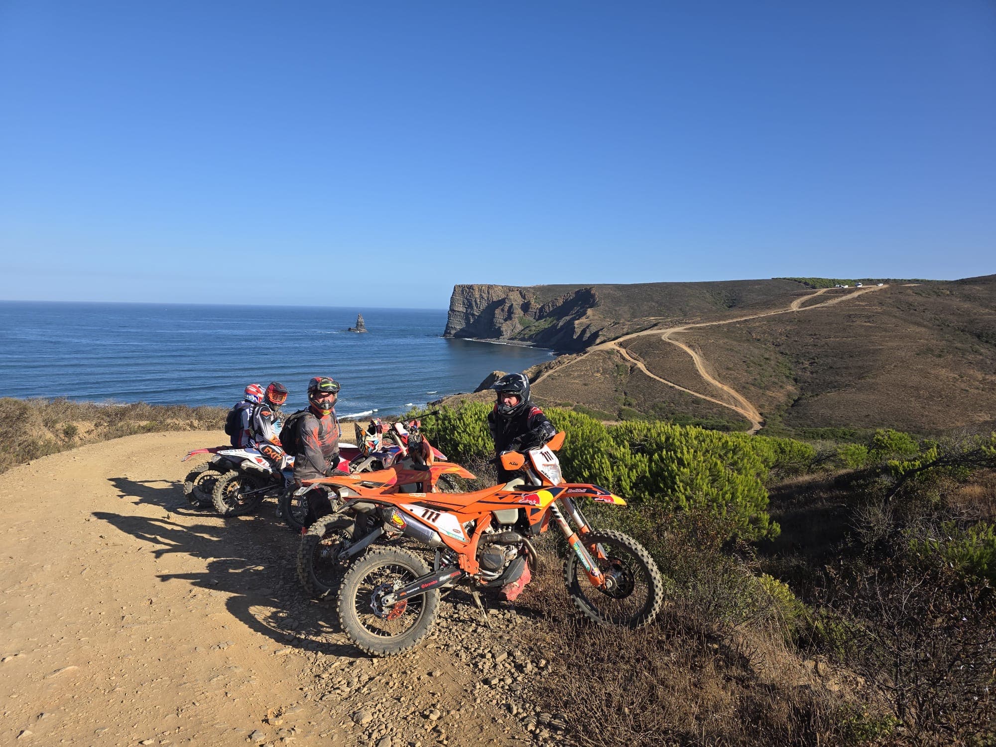 Enduro riders on a coastal ridge trail above the Atlantic